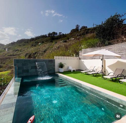a swimming pool with an umbrella and some chairs and an umbrella at Villa balcón de azuaje in Moya
