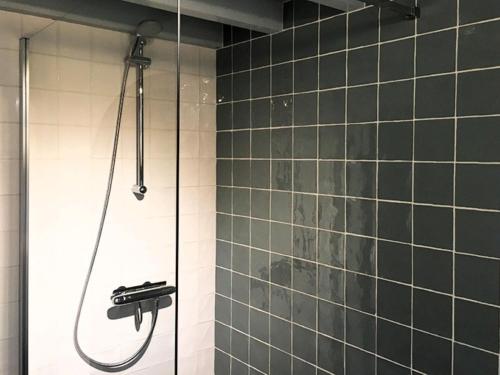 a shower in a bathroom with green tiles at Boerderijte De Lytse Formerum in Formerum