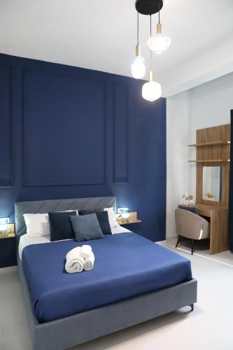 a blue bedroom with a bed with towels on it at Alcenide Aparthotel in Villa San Giovanni