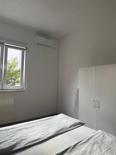 a white bedroom with a bed and a window at La Bocca Apartment - Sarajevo Airport, Private Parking, 2 ACs in Sarajevo