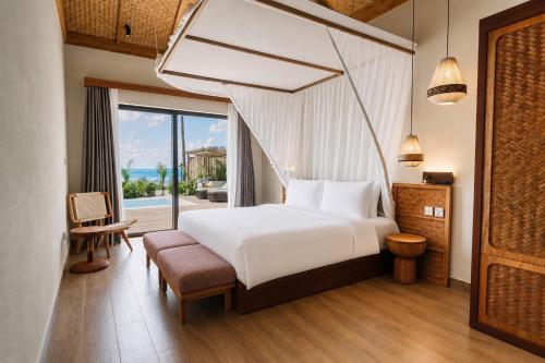 a bedroom with a white bed and a large window at ENVI Paje Wellness Lodge in Paje