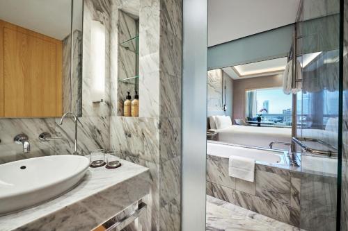 a bathroom with a sink and a bath tub at Carlton Hotel Singapore in Singapore