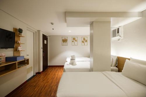 a hotel room with two beds and a flat screen tv at MySpace Hotel @BGC in Manila