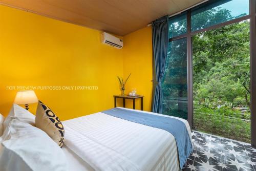 a bedroom with a bed and a large window at Catba Papillon Garden Bungalows & Resort in Cat Ba