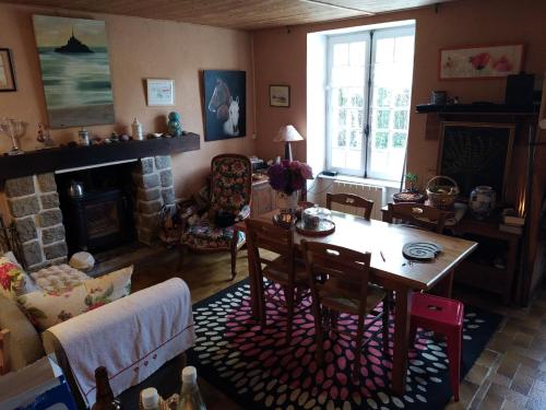 ein Wohnzimmer mit einem Tisch und einem Kamin in der Unterkunft Les Douitils in Saint-Sauveur-la-Pommeraye