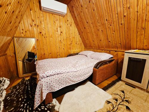 a bedroom with a bed in a wooden room at Căsuța Elena Refugiu în Natură in Buceş