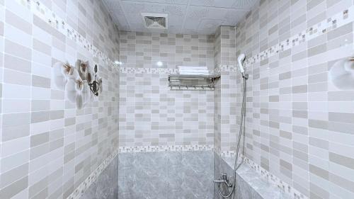 a tiled bathroom with a shower with a glass door at Hà Tiên Hạnh Phúc Hotel in Hà Tiên