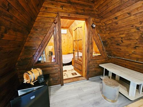 a room with a wooden cabin with a table and a bench at Căsuța Elena Refugiu în Natură in Buceş