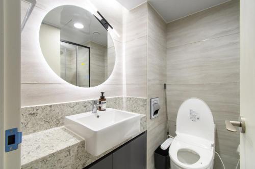 a bathroom with a sink and a toilet and a mirror at 플럼바고올스위트1407 in Chosan-ni