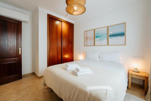 a bedroom with a white bed with two towels on it at Villa Volcano by CasasBlancas in Yaiza