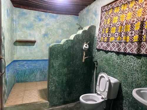 a bathroom with a toilet and a painting on the wall at Mustapha' s Place in Bwejuu