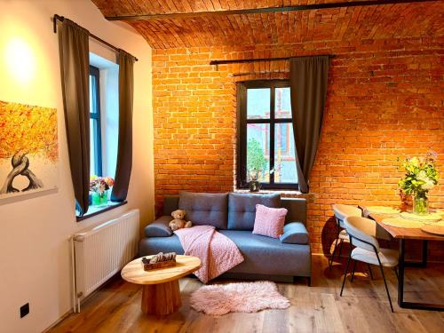 a living room with a blue couch and a brick wall at Apartmány CHATTA in Horní Maršov