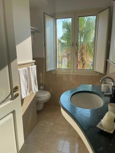 ein Badezimmer mit Waschbecken, Toilette und Fenster in der Unterkunft Kento Resort in Centuripe