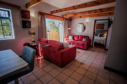 a living room with red furniture and a bedroom at Serenity Cottage in Swellendam