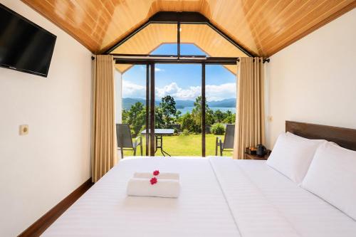 a bedroom with a white bed and a large window at Royal Indah Glamping Kintamani in Kintamani