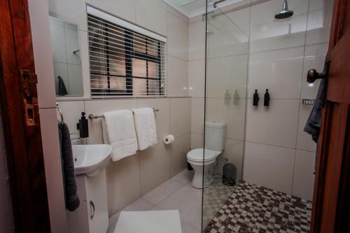 a bathroom with a toilet and a glass shower at Serenity Cottage in Swellendam