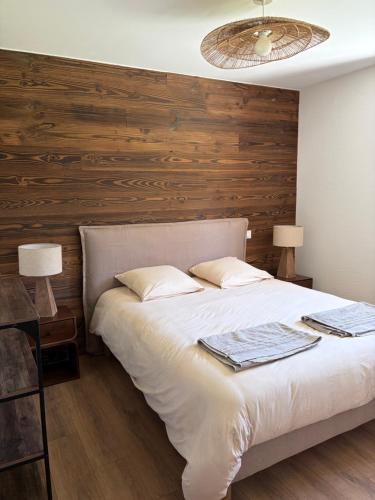 a bedroom with a large bed with a wooden wall at Le Chalet du Soleil Levant in Longevilles-Mont-dʼOr