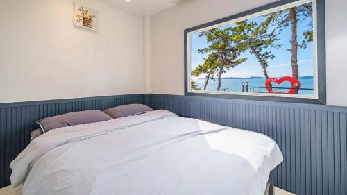 a bedroom with a bed and a large window at Mu-an Prejong Dokchae Pension in Muan