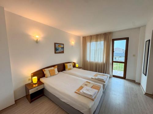 a bedroom with a large bed and a large window at Семеен Хотел Примо Family Hotel Primo in Primorsko