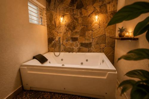 a bath tub in a bathroom with a stone wall at Ayana Lake Resorts in Kovillūr