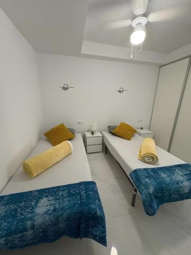 two beds in a room with blue and yellow pillows at Marys Place in Costa Del Silencio