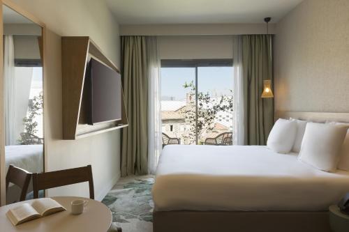 a hotel room with a bed and a table and a window at MERCURE NIMES CENTRE ARENES in Nîmes