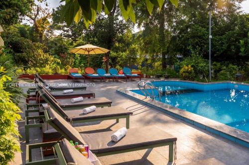 a swimming pool with lounge chairs and an umbrella at Catba Papillon Garden Bungalows & Resort in Cat Ba