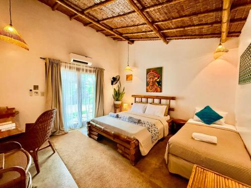 a bedroom with two beds and a desk and a window at The Kokomo Siargao in General Luna