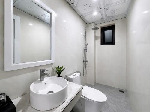 a white bathroom with a sink and a toilet at Moonland Hotel in Phương Lăng