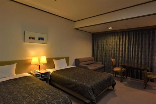 a hotel room with two beds and a chair at Miyajima Morinoyado in Miyajima