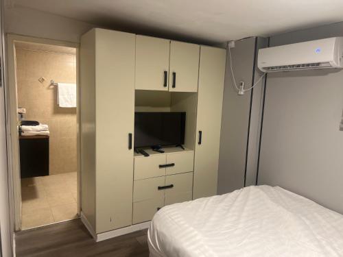 a bedroom with a bed and a tv and a bathroom at בית הקונגרס גבעת אולגה in H̱adera