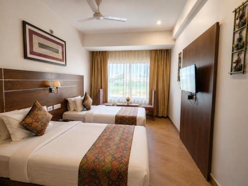 a hotel room with two beds and a window at Amritara Ramila Kutir Ayodhya in Ayodhya