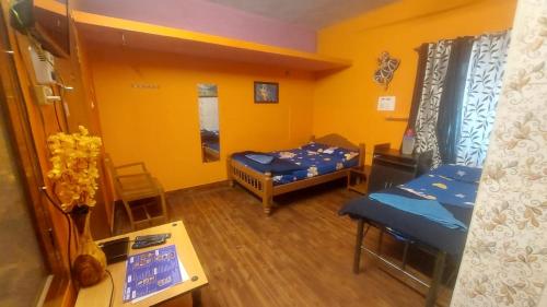 a small room with two beds and a table at Honey Palace Homestay in Madikeri