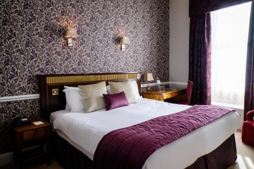 een slaapkamer met een groot bed en een paarse deken bij Old Hall Hotel in Buxton