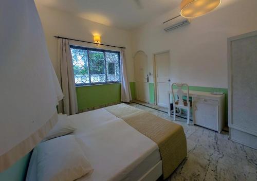 a bedroom with a bed and a window and a desk at Beach villa Candolim in Candolim