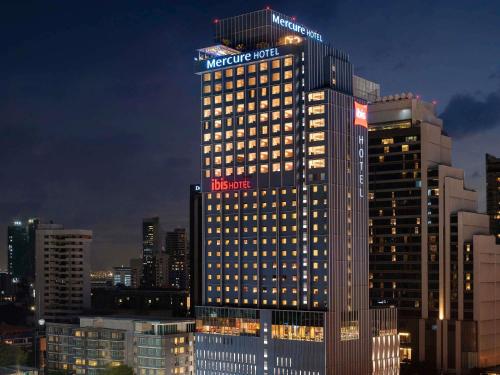 a lit up building in a city at night at ibis Bangkok Sukhumvit 24 in Bangkok