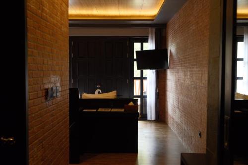 a room with a bed and a television and a brick wall at JL World Hotel Dili in Dili