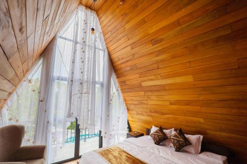 a bedroom with a wooden wall with a bed and a window at The Glade in Weligama
