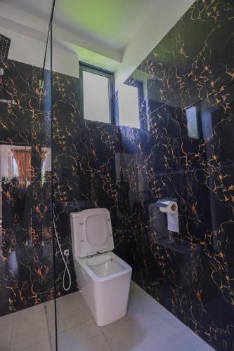 a bathroom with a toilet and a black marble wall at The Glade in Weligama