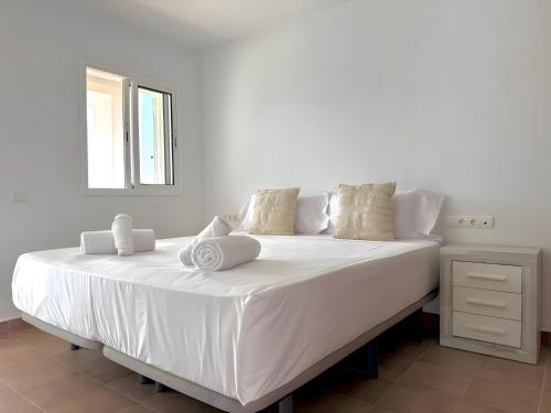 a large white bed with white sheets and pillows at Villa Can Alaya in Santa Eularia des Riu