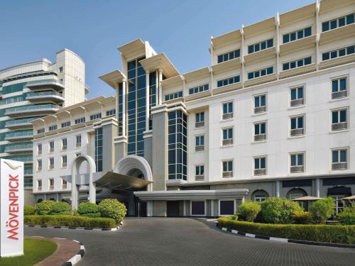 a large white building with a sign in front of it at Mövenpick Hotel & Apartments Bur Dubai in Dubai