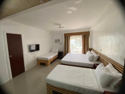 a hotel room with two beds and a television at Dapdap Shorelines Beachfront Villa in Camotes Islands