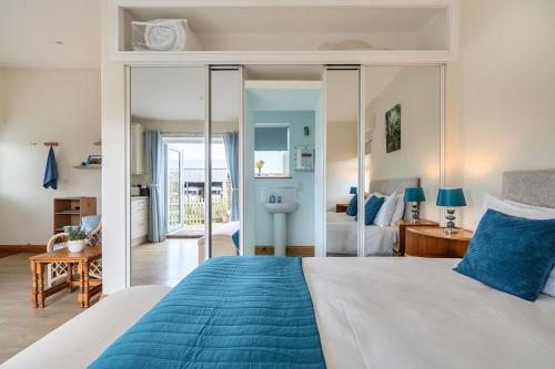 a bedroom with a blue and white bed and a bathroom at Ashclose Lodge Annexe in Sherborne