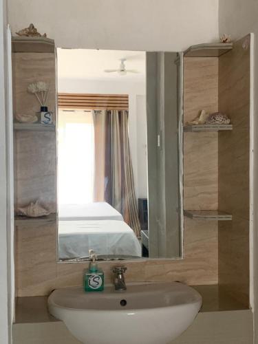 a bathroom with a sink and a mirror and a bed at Dapdap Shorelines Beachfront Villa in Camotes Islands