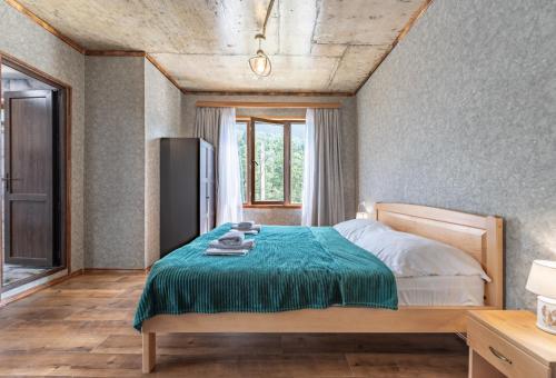 a bedroom with a bed with a green blanket at Muros Guesthouse in Mestia