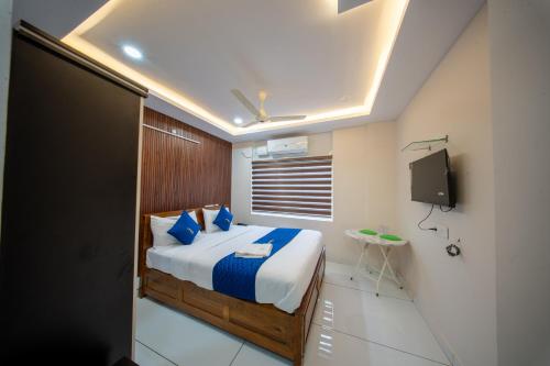 a bedroom with a bed with blue pillows and a tv at BREEZA GRANd in Kazhakuttam