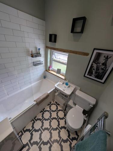a bathroom with a tub and a toilet and a sink at Quaint Cottage in Charming Evesham in Evesham