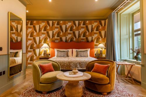 a bedroom with a bed and two chairs at The Mill House in Stewarton