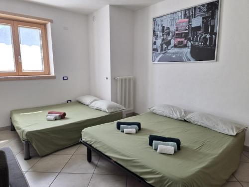 two beds in a room with a picture on the wall at Appartamento da Nonna Anna in Montagna in Valtellina