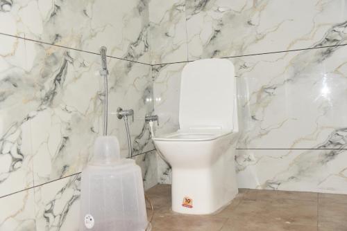 a bathroom with a white toilet and marble walls at D D Luxury Inn in Chikmagalūr